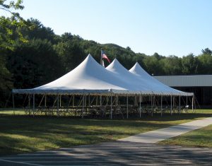 30x60 Pole Tent set with tables and chairs for a corporate event with american flag in the background.